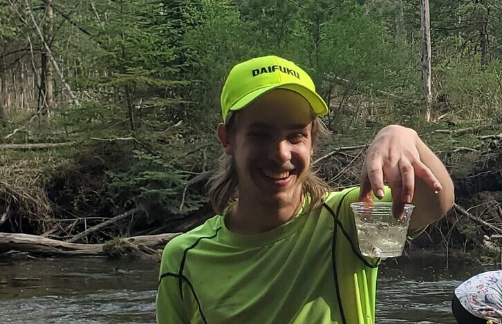 Student holding a cup with a salmon in it, about to release into Boyne River