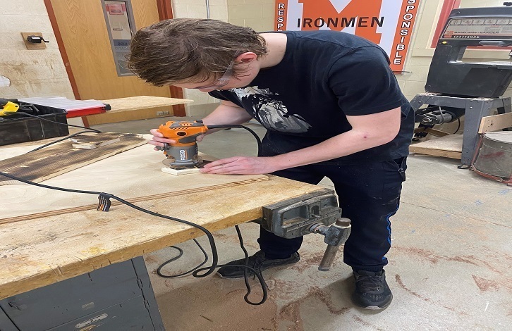 Student using a machine in woodshop class
