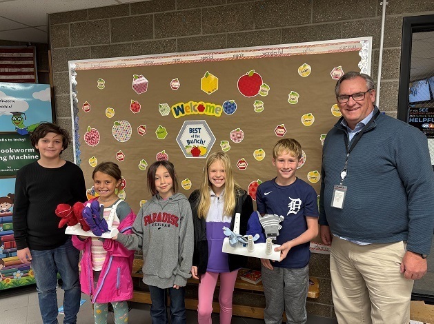 Elementary students holding up their mitten warmers  donated by Consumers Energy